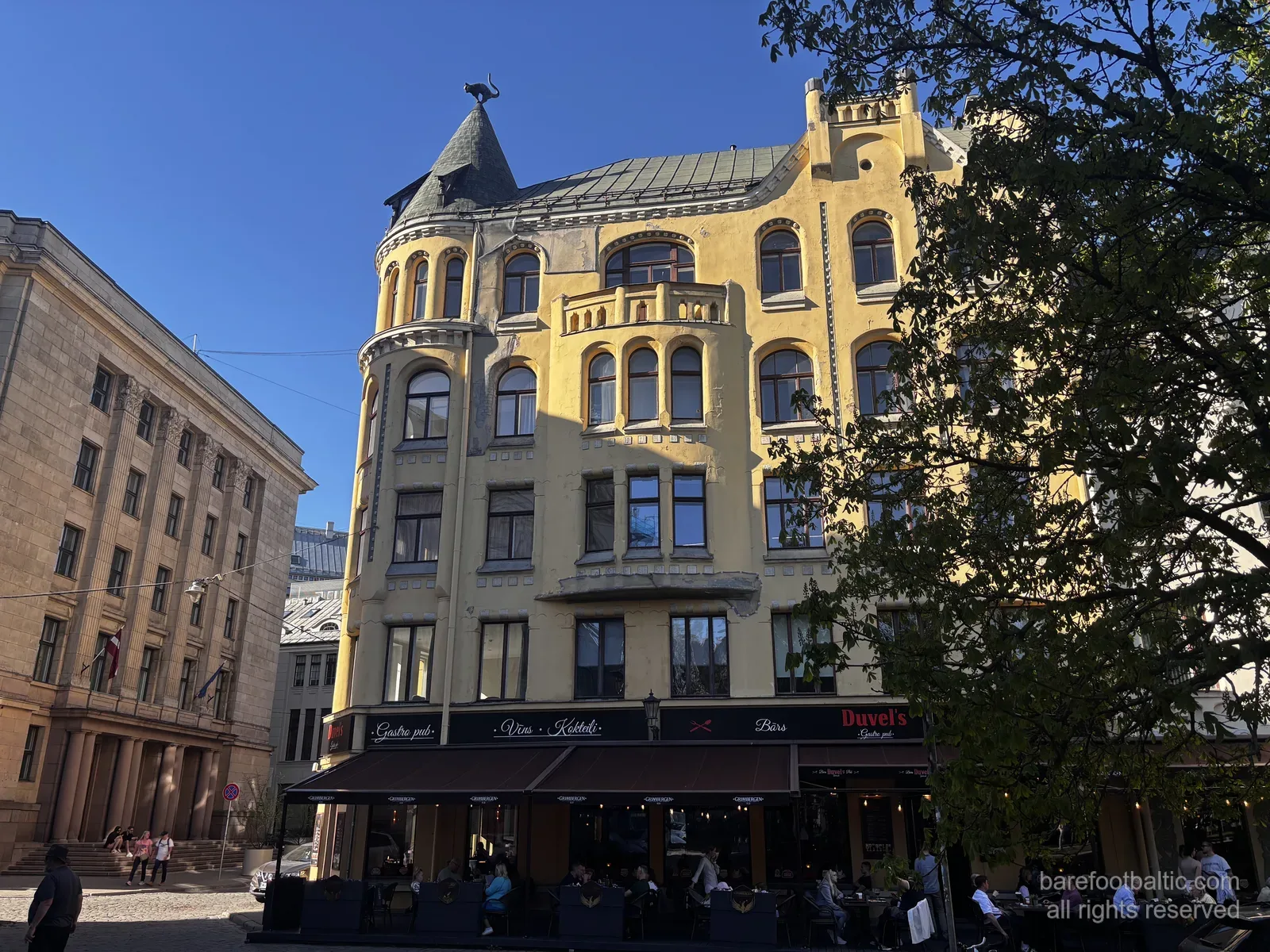 The Cat House (Kaķu nams) on Meistaru iela in Riga Old Town, with its yellow Art Nouveau facade and the bronze cat on the corner turret, Latvia.