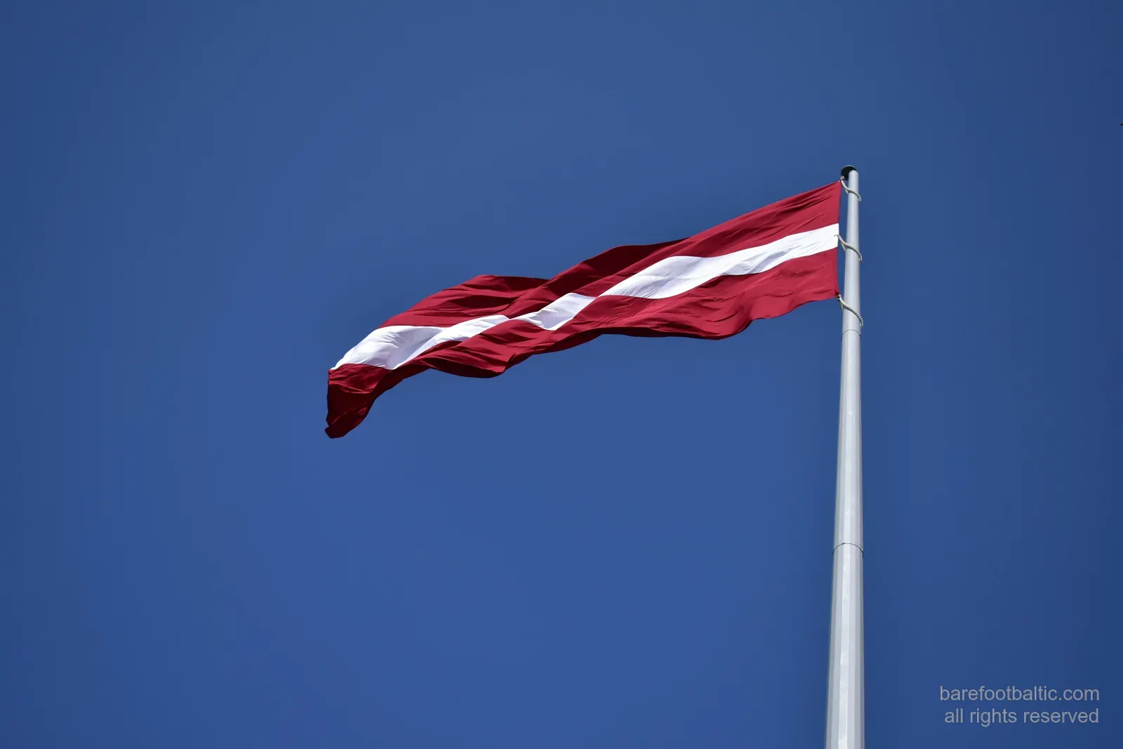 The Latvian flag against a blue sky, the carmine-red and white that Porziņģis wore on his shoulders at the 2024 NBA Finals