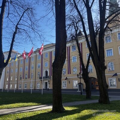 Pils laukums pavasarį su pilies vėliavomis tarp pliki medžių, Rīga, Latvija