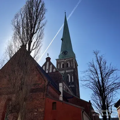 Il campanile della cattedrale di San Giacomo dal basso con una scia di condensazione nel cielo, Riga, Lettonia