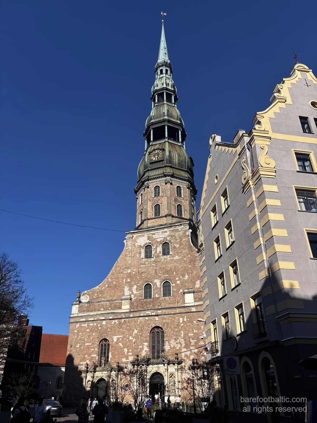 St Peter's Church (Sv. Pētera baznīca) with its tall green spire against a blue sky in Riga Old Town, Latvia.
