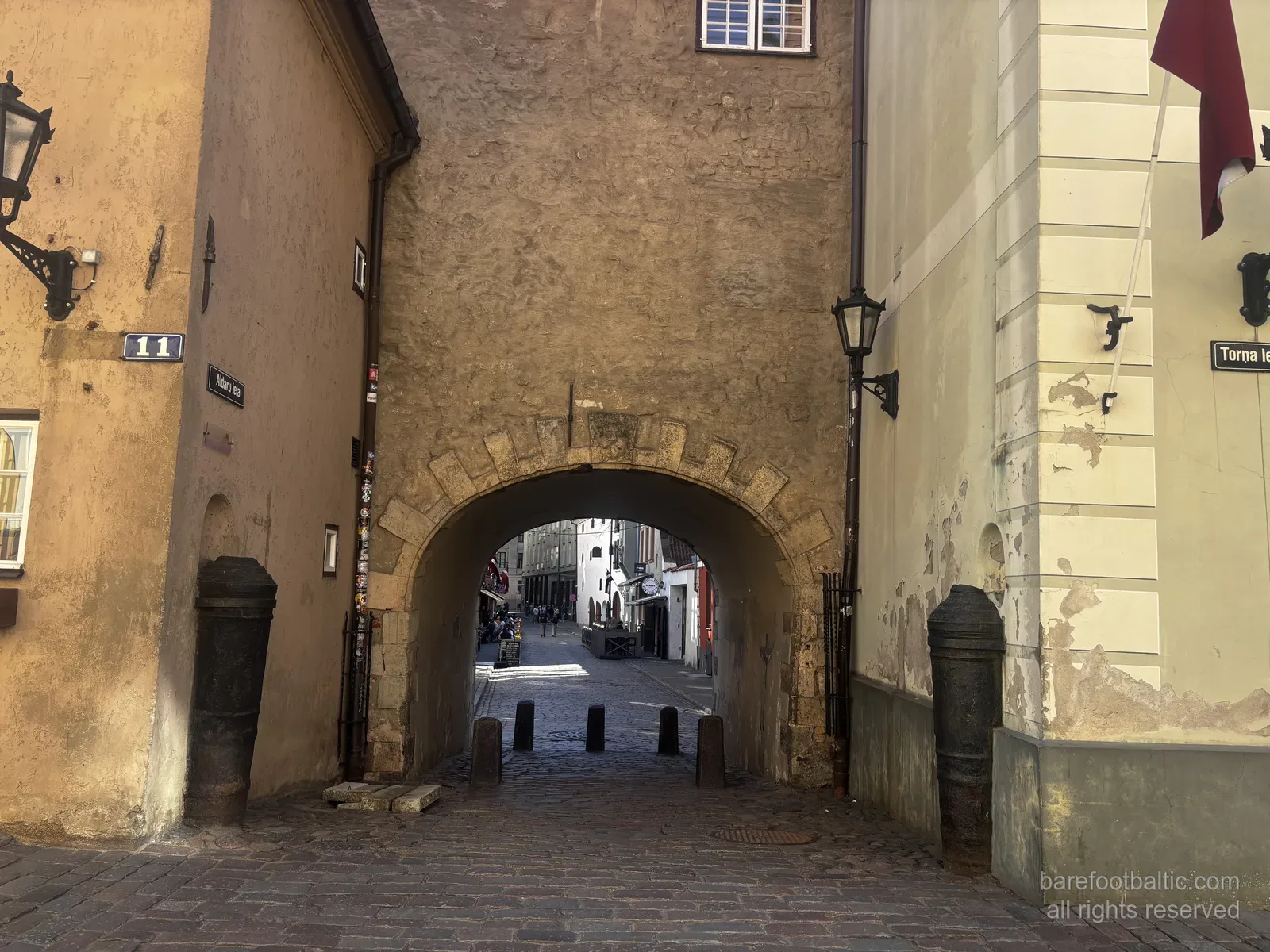 The Swedish Gate (Zviedru vārti) on Torņa iela in Riga Old Town, Latvia — a stone archway between two yellow buildings.