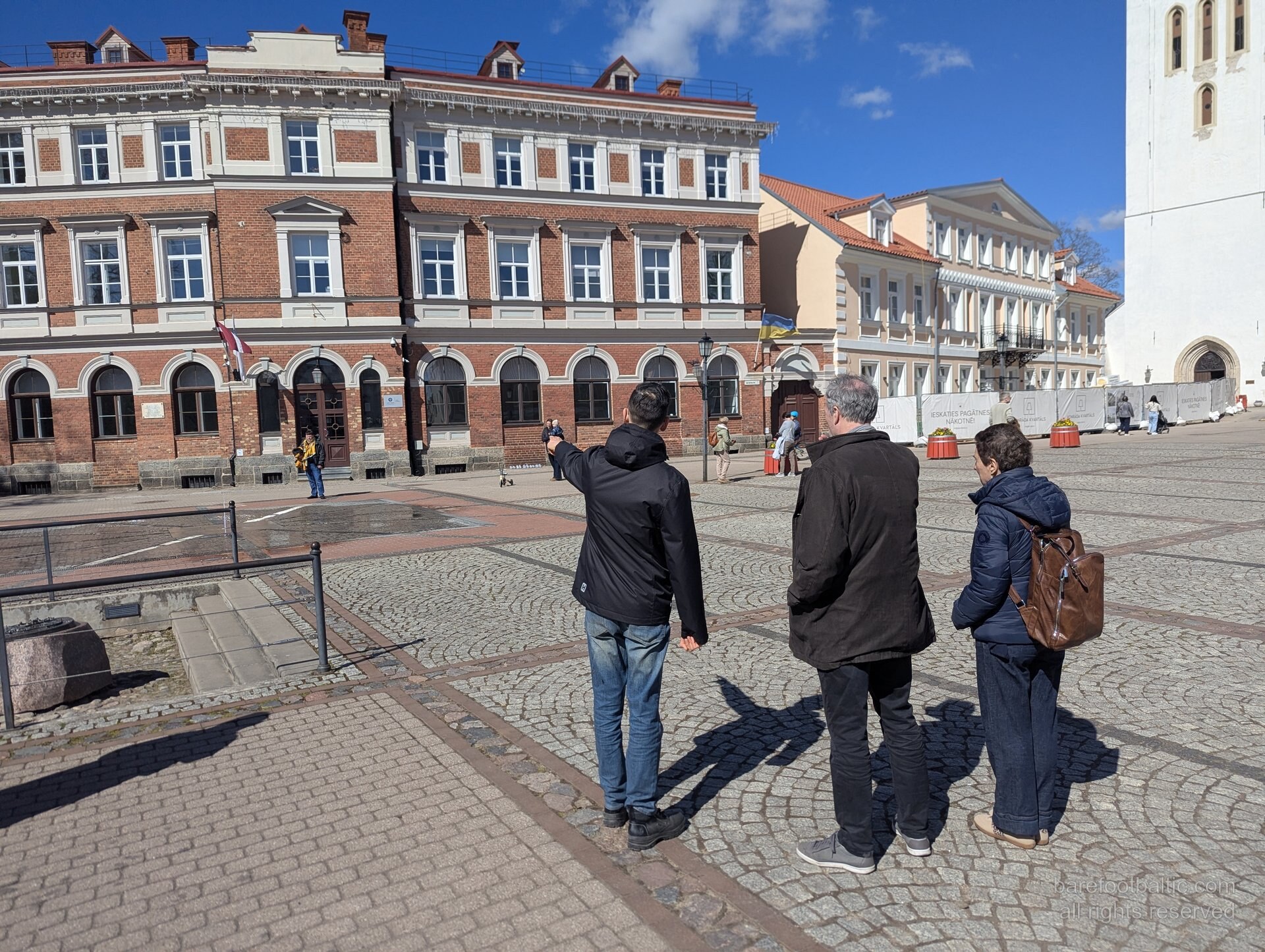 The central square of Cēsis Old Town with a small tour group, cobblestones and historic buildings, Latvia